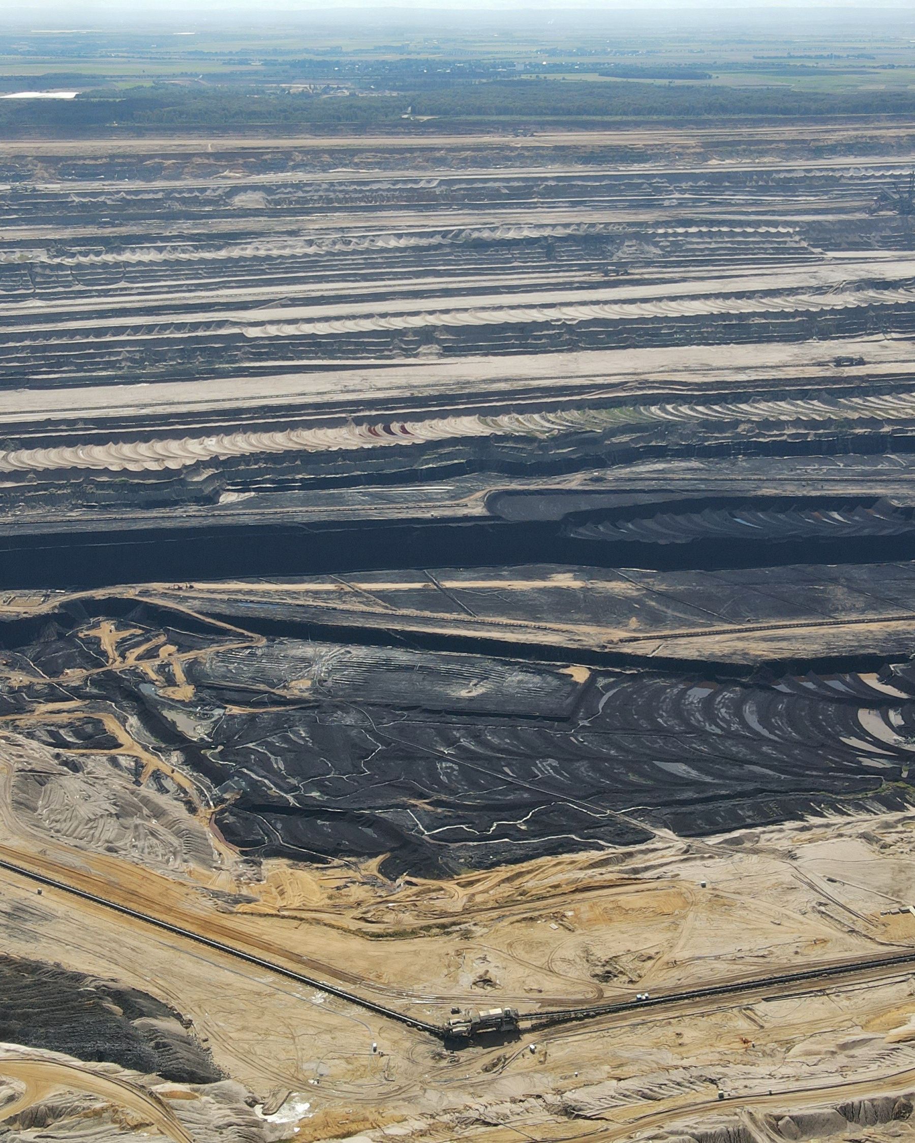 An aerial shot of a flat coal mine, with alternating dark and light swaths.