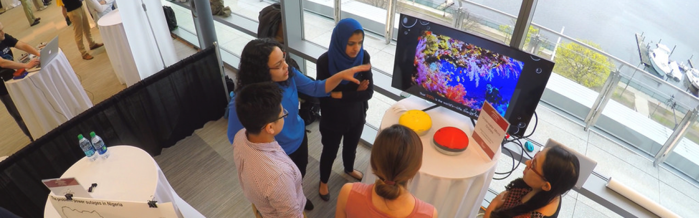 Students gather around a display of a coral reef at an MIT event