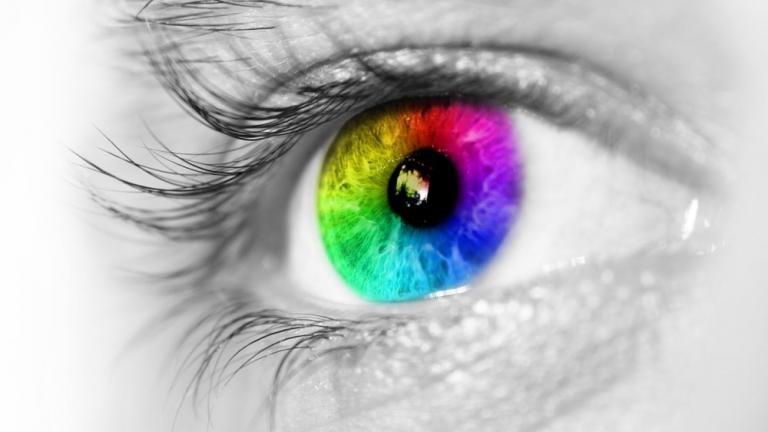 Photo of human eye with the iris in a rainbow of colors.