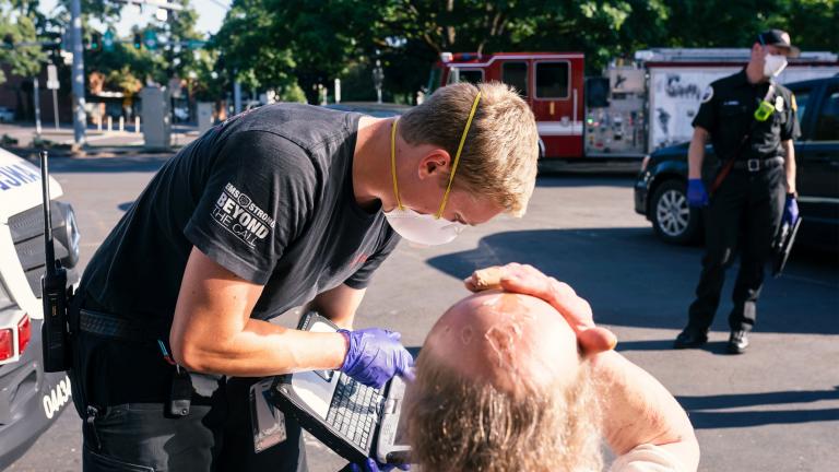 A paramedic treats a man experiencing heat exposure during the heatwave in Salem, Ore.