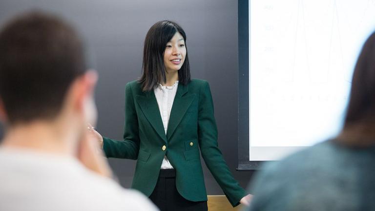 Jing Li, an assistant professor of applied economics, engages with her students during the Electricity Strategy Game debrief.