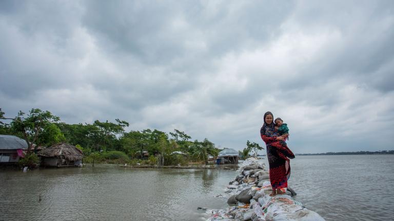 For the coastal country of Bangladesh, once-in-a-century storm tides could strike every 10 years — or more often — by the end of the century, scientists report. In this photo, a Bangladeshi woman and child walk over the top of a sandbag embankment in Khulna on May 4, 2019.