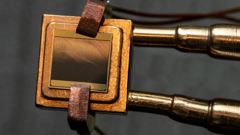 A thermophotovoltaic (TPV) cell (size 1 cm x 1 cm) mounted on a heat sink designed to measure the TPV cell efficiency. To measure the efficiency, the cell is exposed to an emitter and simultaneous measurements of electric power and heat flow through the device are taken.