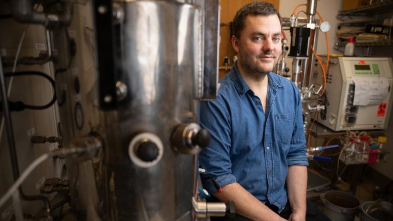 Daniel Suess sits among lab machinery.