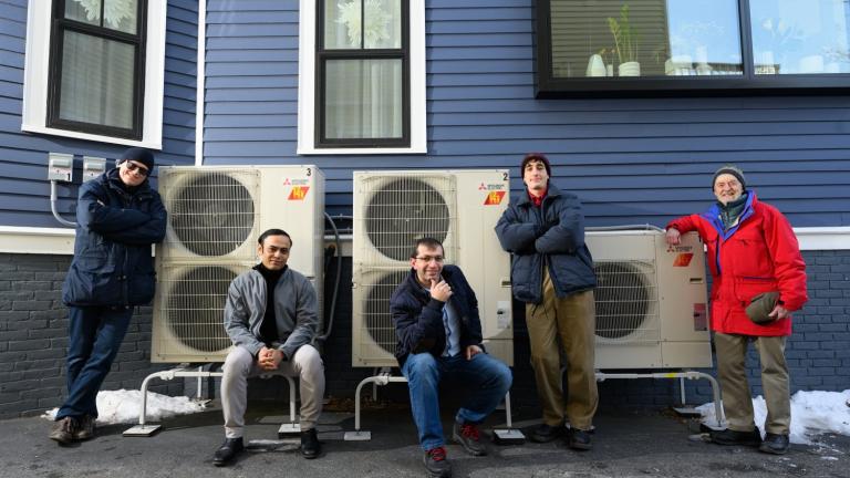 A modeling study by an MIT team has shown that electrifying residential heating can be a substantial step toward reducing carbon emissions, as well as costs, over the combined electricity and natural gas sectors. Here, the team poses beside a high-efficiency electric heat pump system that provides heating to the home, replacing the natural gas-fired furnace. Left to right: Audun Botterud, Saurabh Amin, Rahman Khorramfar, Morgan Santoni-Colvin, and Leslie Norford. Not pictured: Dharik Mallapragada.