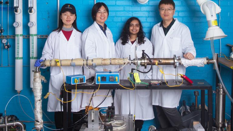 Left to right: Graduate student Chuwei Zhang, Assistant Professor Sili Deng, graduate student Maanasa Bhat, and postdoc Jianan Zhang stand behind the lab-scale apparatus they use to investigate a low-cost method of synthesizing materials critical for manufacturing lithium-ion batteries.