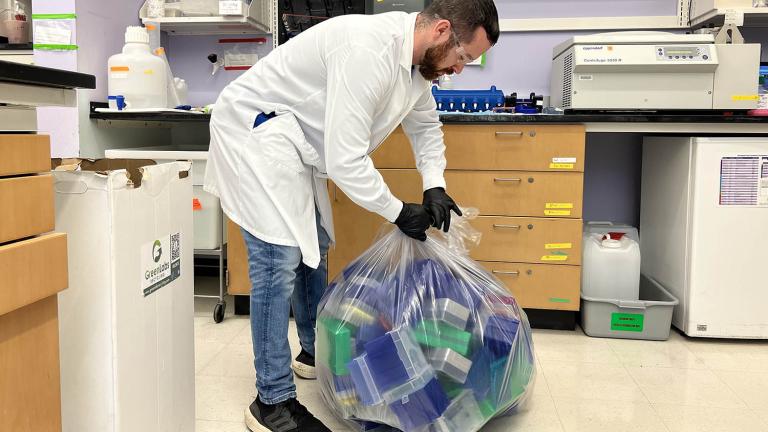 Normand Desrochers, MIT EHS technician, picks up pipette tip boxes and conical tube racks to be recycled.