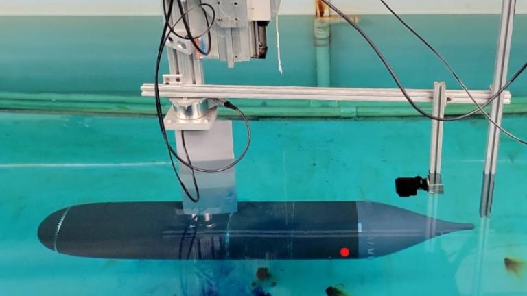 Initial experimental setup, showing the submerged axisymmetric model rigidly attached at about mid-length to the towing carriage through a streamlined strut.