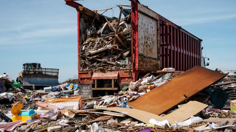 A large red truck drops off trash into a pile on the South Kent County Landfill.
