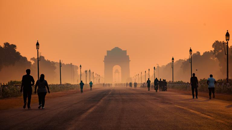 People walk along a road toward the India Gate in Delhi, shrouded in smog.