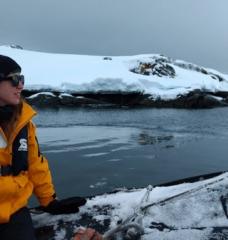 Emily Moberg sits on the edge of a boat while doing field research in a snowy climate.
