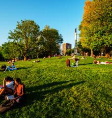 People relax on the Boston Common lawn beneath the Soldiers and Sailors Monument.