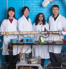 Left to right: Graduate student Chuwei Zhang, Assistant Professor Sili Deng, graduate student Maanasa Bhat, and postdoc Jianan Zhang stand behind the lab-scale apparatus they use to investigate a low-cost method of synthesizing materials critical for manufacturing lithium-ion batteries. 