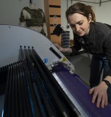 At Lincoln Laboratory’s Defense Fabric Discovery Center, Erin Doran demonstrates how reflective fibers can be woven into textiles. Such fibers could function as indelible, scannable labels to easily sort fabrics for recycling. 