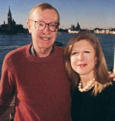 On the left is Peter stone in a red sweater, with his arm around Paola Malanotte-Rizzoli in a black shirt. Behind them in a distant view of some buildings in Venice