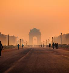 People walk along a road toward the India Gate in Delhi, shrouded in smog. 